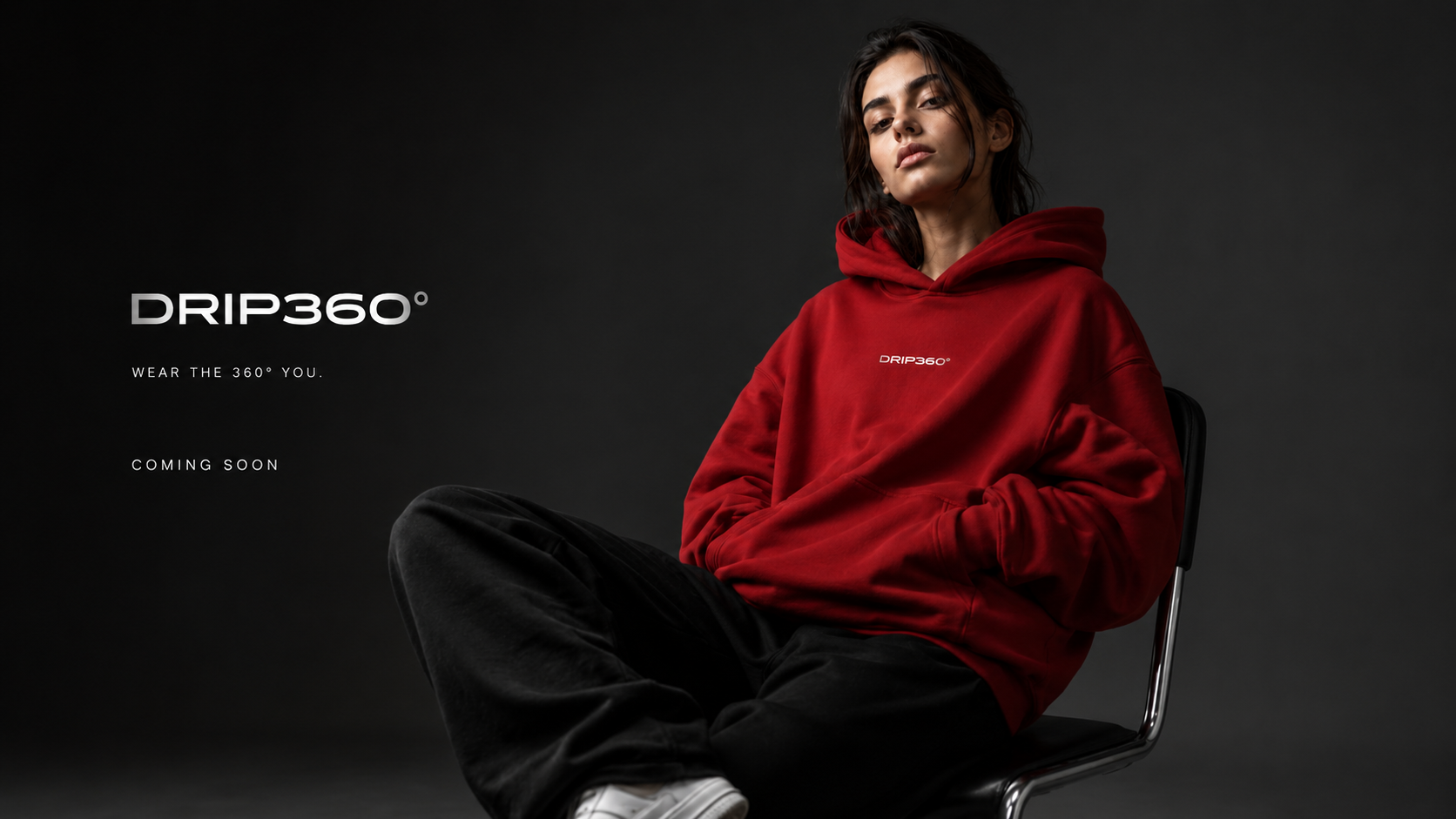 Model seated wearing the DRIP360° hoodie in deep red