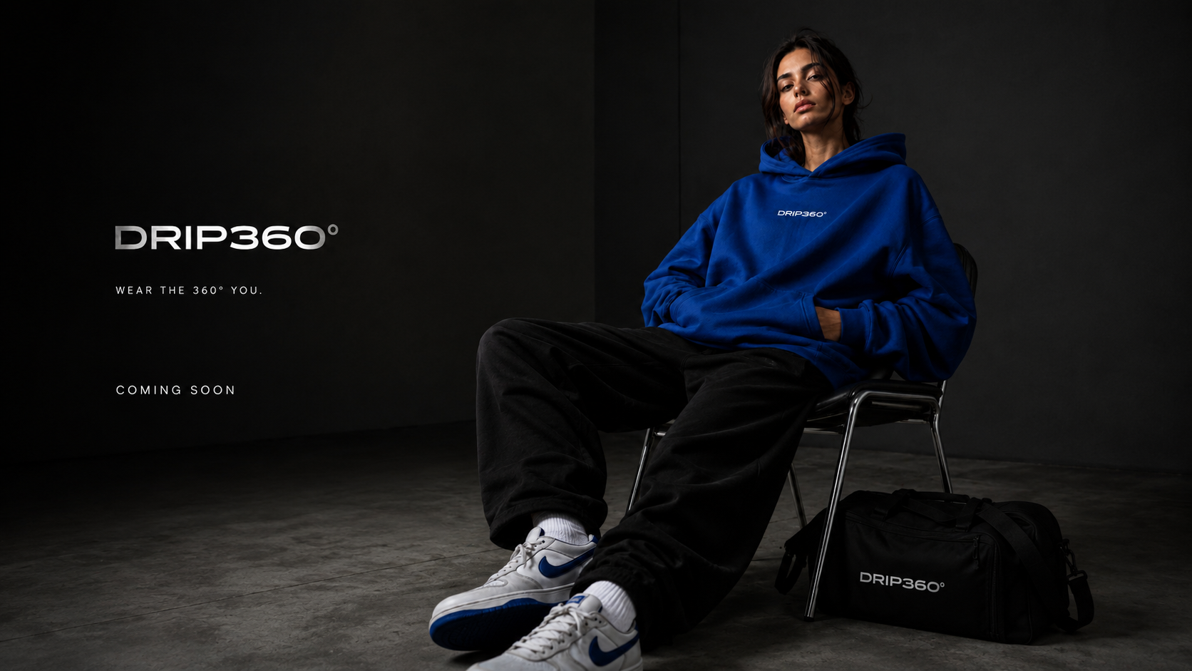 Model wearing the DRIP360° hoodie in cobalt blue with duffel bag